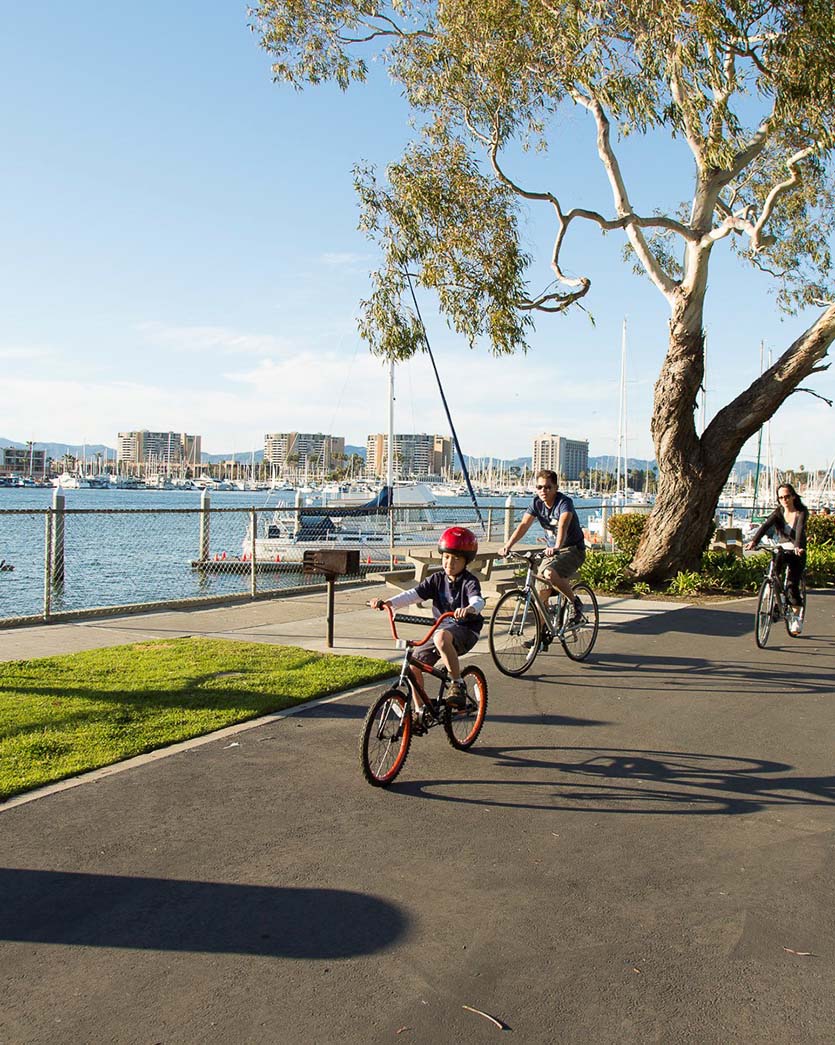 parents and young boy bike riding at the beach