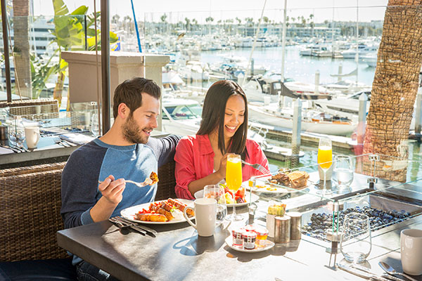 couple eating brunch on outdoor patio with marina in background