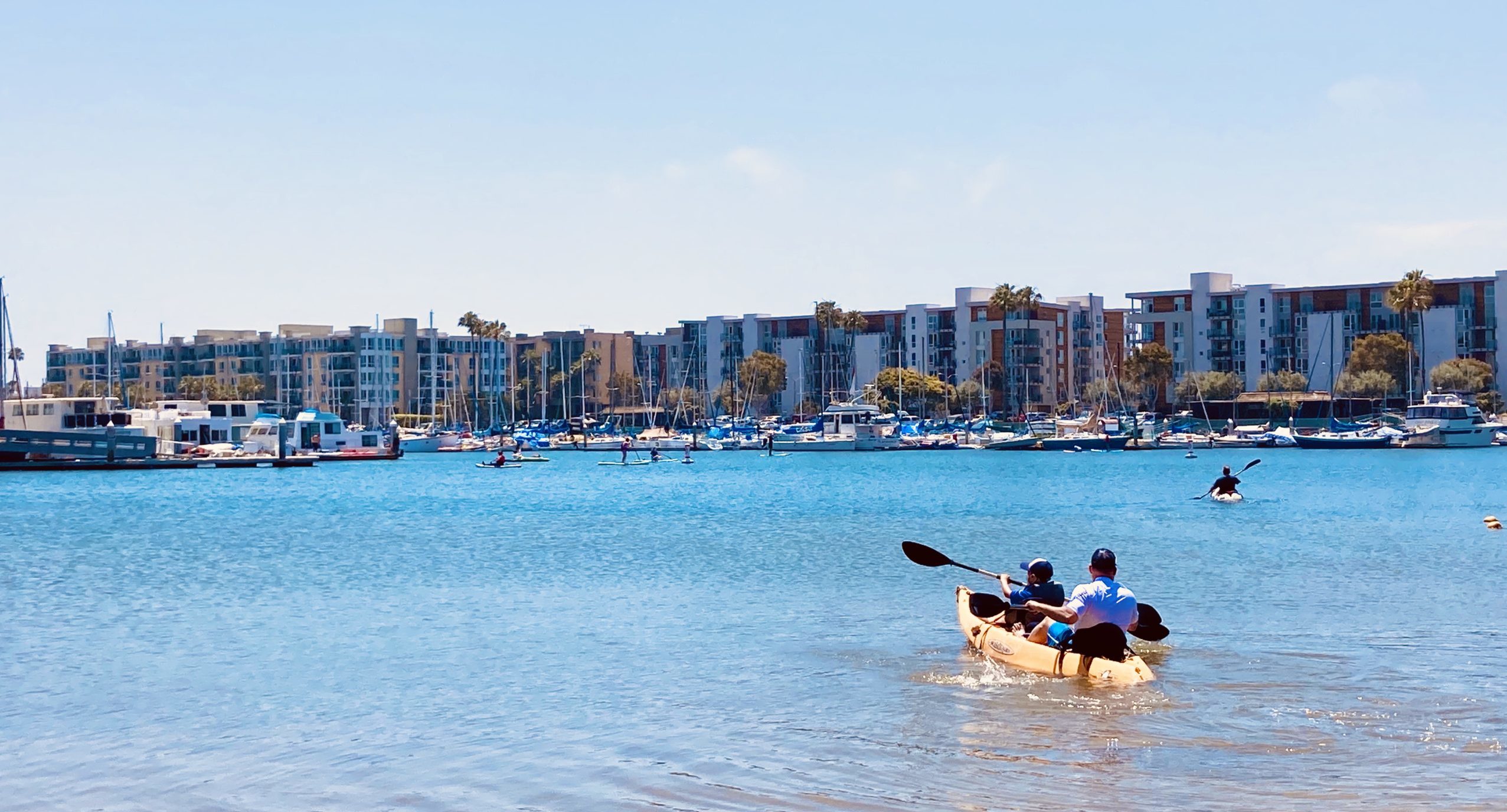 father and son go kayaking at mother's beach in marina del rey