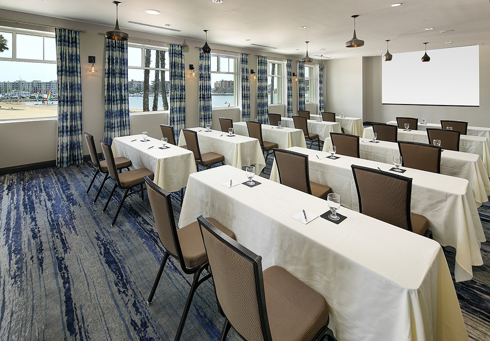 rectangular conference tables with chairs and presentation screen in front