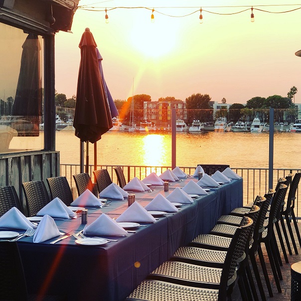 Table set for small party on outdoor patio facing the water and sunset